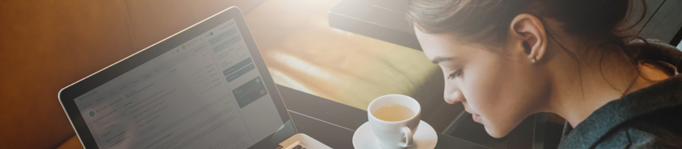 profile of woman sitting at desk with laptop and tea